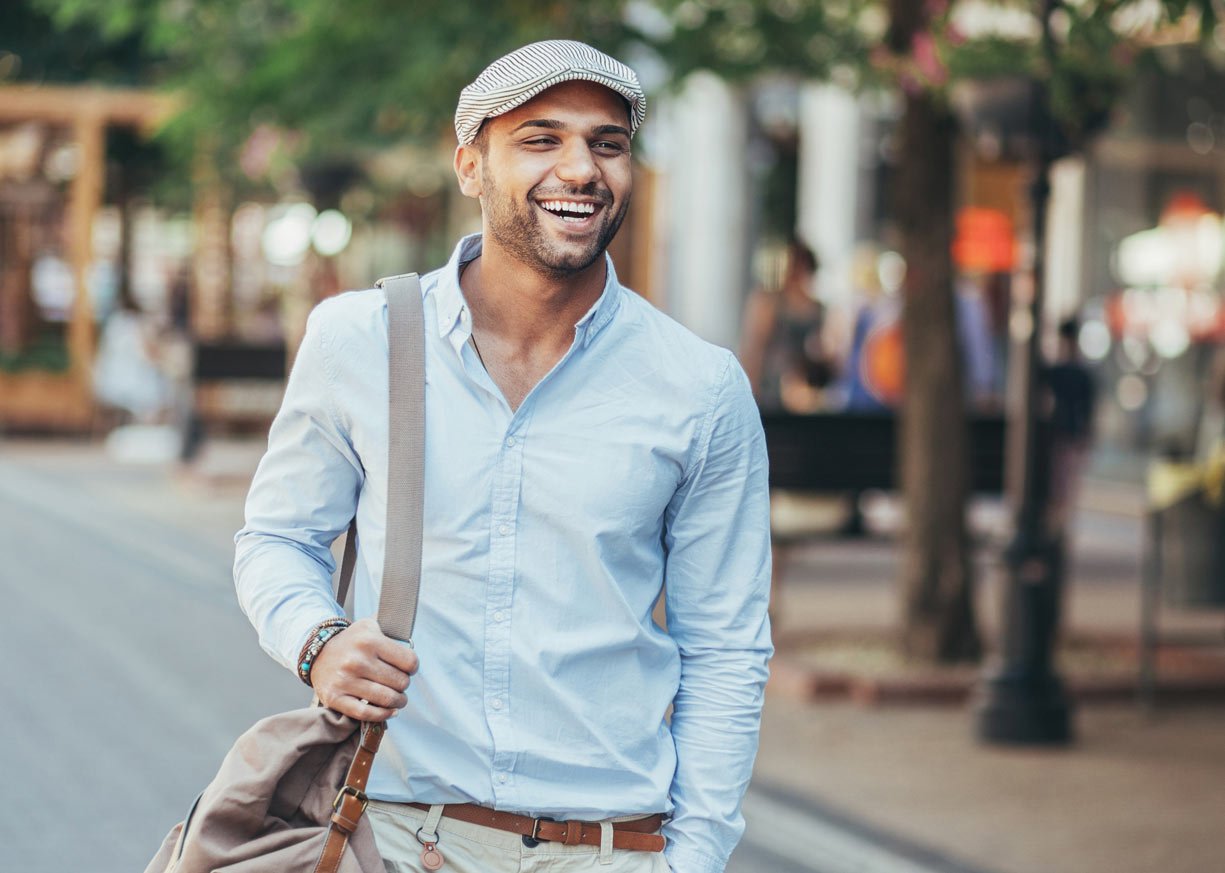 A young man walking and smiling thinking about New National Bank loans, deposits, and charitable giving statistics